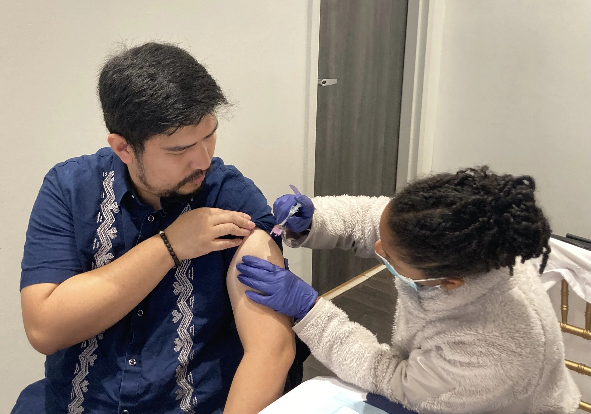   A guest to the embassy gets his flu shot in a room housing a new art exhibition. Photo by Diplomatica Global Media.   